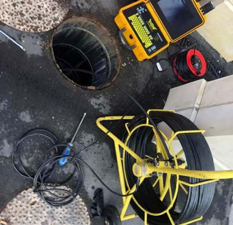 CCTV drain camera reel and monitor set up beside an open manhole