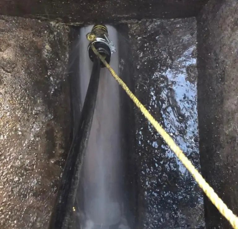Jetting hose clearing the channel at the base of an inspection chamber