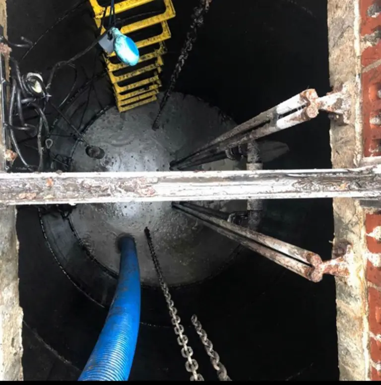 Looking down a deep brick manhole during a sewer clearance