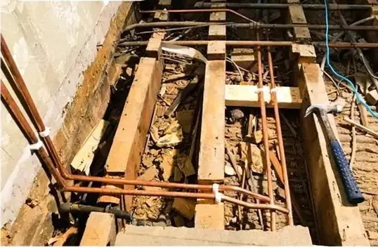 Copper pipework exposed under lifted floorboards.